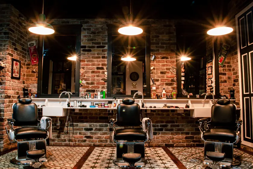 Interior de una barbería con sillones de cuero y pared de ladrillo