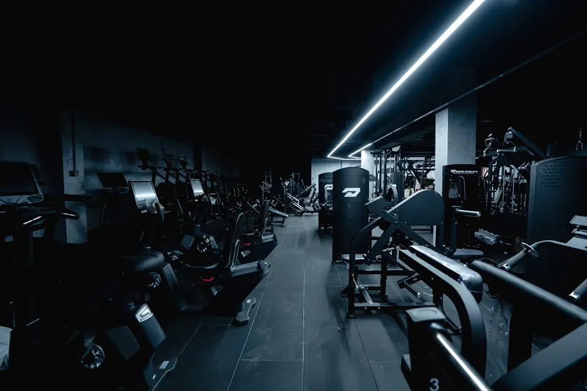 Interior oscuro de un gimnasio con máquinas de entrenamiento